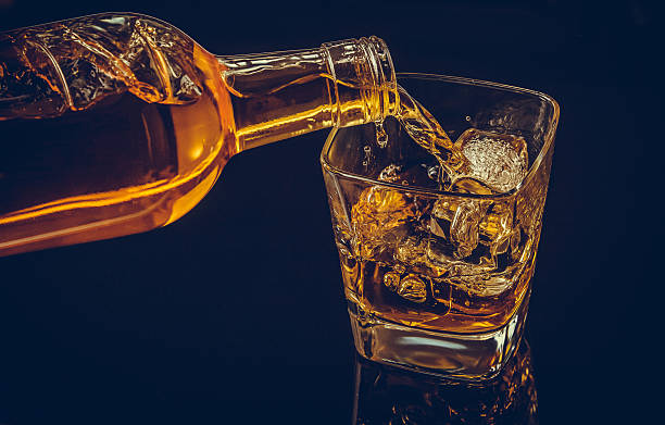 istock barman pouring whiskey with ice cubes in glass 619072966