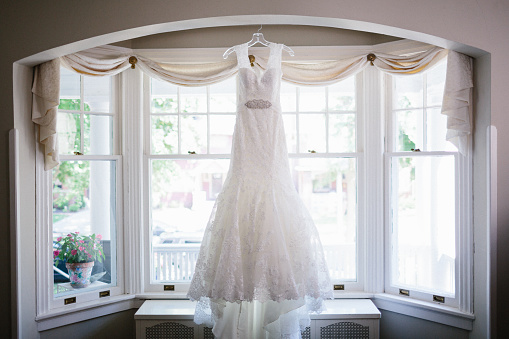 A wedding dress hanging in a window