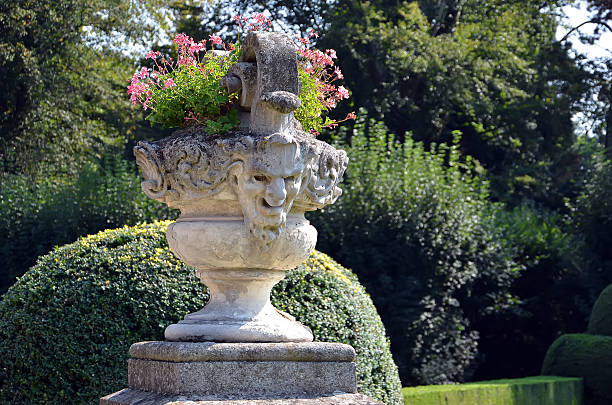 Replica of a Roman statue with several defects and some Roman columns also placed in my garden. They are right in front of a wall full of plants. Copy Space