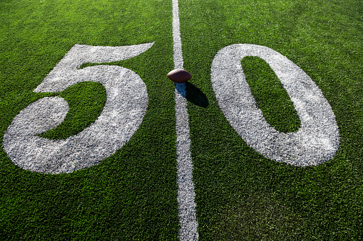 American football on grass, close-up of fifty yard line