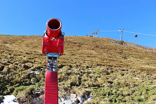 Snow cannon in the Gastein mountains, in October.  A cable car in the background. The Gastein mountains are part of the Hohe Tauern, Austria, Europe.
