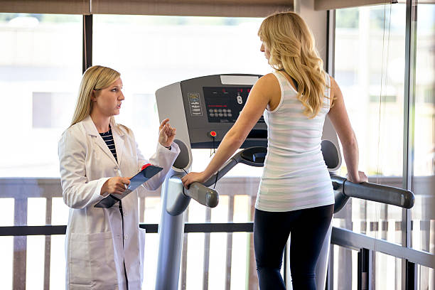 istock Female physical therapist talking with female patient on treadmill 619079260