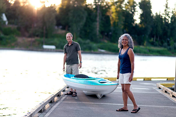 istock Ethnic diverse elderly couple carrying kayak to water 619080290