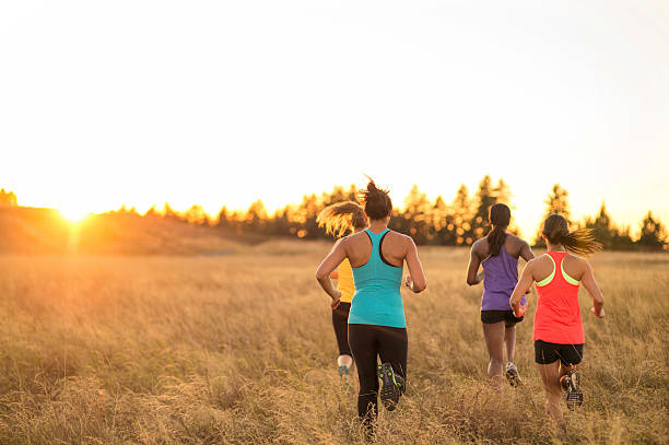 istock Group of diverse female athletes trail running in tall grass 619081214
