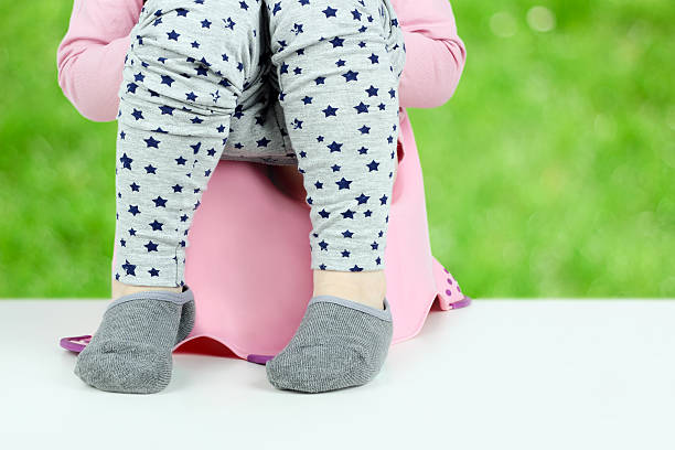istock Children's legs hanging down from a chamber-pot on a green 619084306