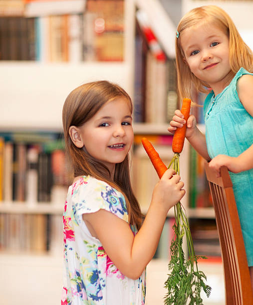istock Little smiling girls with carrots 619086912