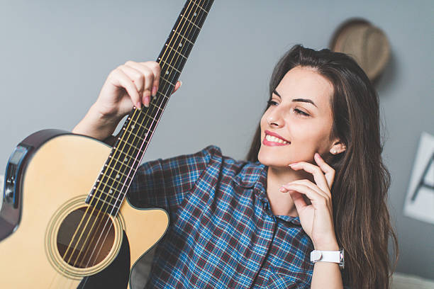 istock Young woman on sofa holding guitar 619087094