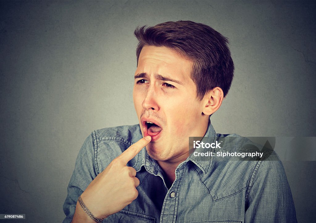disgusted man with finger in mouth ready to throw up disgusted man with finger in mouth displeased ready to throw up isolated on gray wall background. Human emotion body language Disgust Stock Photo