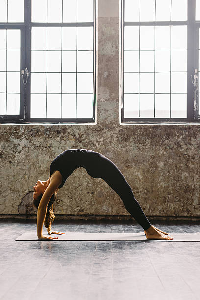 istock Young woman practicing yoga in urban loft: Upward Bow Pose 619089076