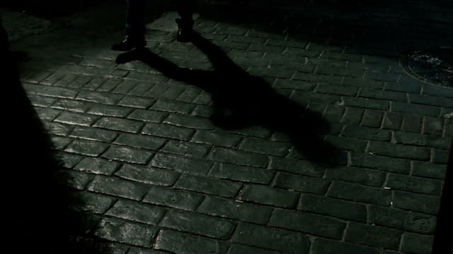 Shadow of a man walking on cobblestone way