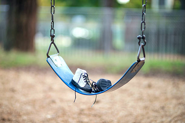 Childs shoes sitting on a swingset at a local park