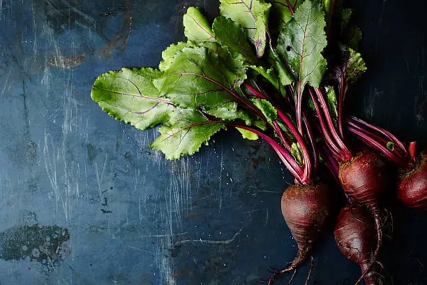 Bunch of beets on dark blue metal surface.
