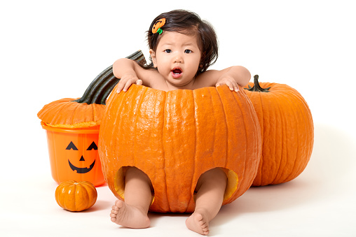 Baby girl in giant pumpkin for Halloween