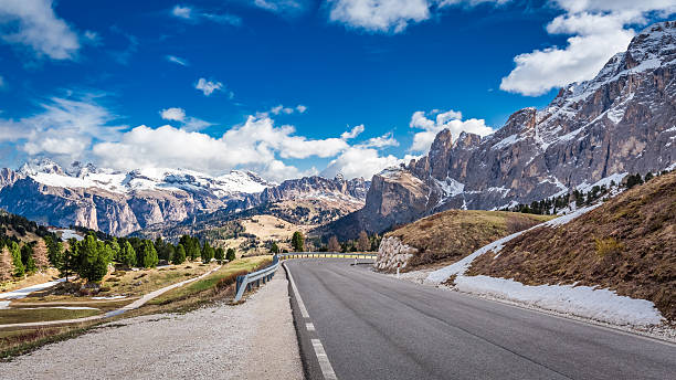 istock Road leading to snow capped Dolomites, Italy 619239480