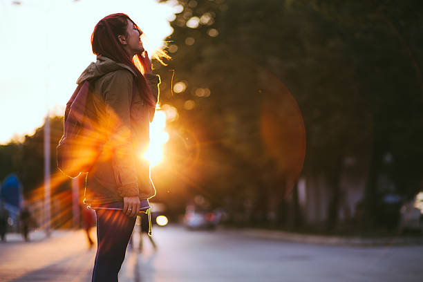 Redheaded Beauty in Sunset Smiling Young Red-haired woman dressed in jacket is enjoying vivid sunset in the streets. early fall stock pictures, royalty-free photos & images