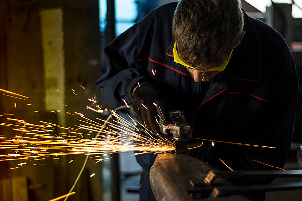istock Manual worker grinding steel table in production hall. 619244748