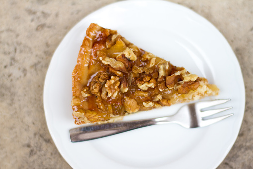 Walnut-apple pie slice with a fork on a white plate background. Copy space available.