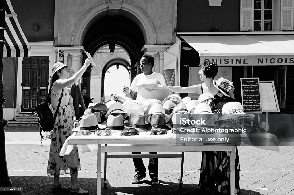 Market stall selling hats Nice, France - July 31, 2015: Two women tourists choosing hats from a market stall in Nice, France. French Riviera Stock Photo