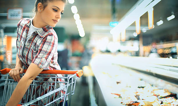 mujer comprando algunos alimentos congelados en el supermercado local. - supermarket women packaging blond hair fotografías e imágenes de stock