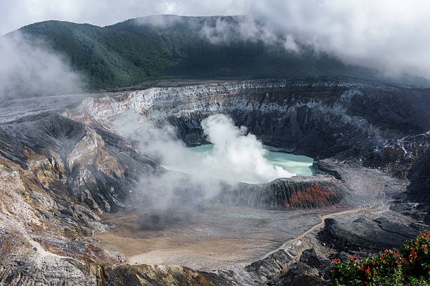 istock Steam erupting from active volcano with mountain range in backgr 619249190