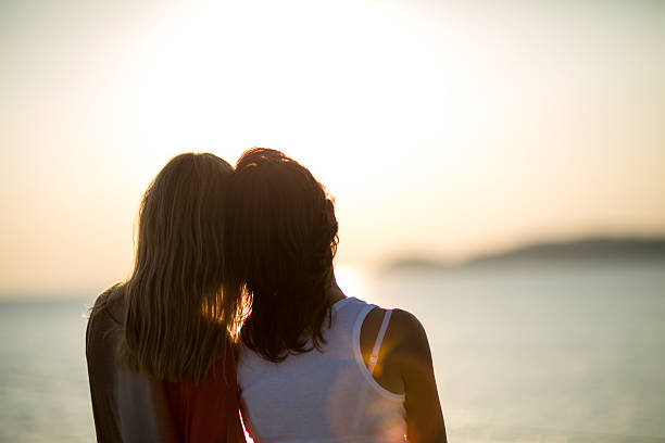 istock Two sisters enjoy in sunset at sea 619250002