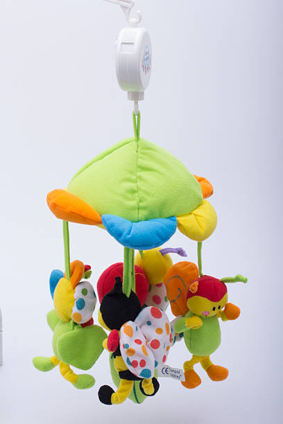A yellow crab shaped children's toy, with small balls inside, makes a loud sound. On red background