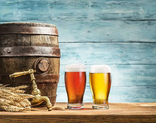 Glasses of  beer and ale barrel on the wooden table. Craft brewery.