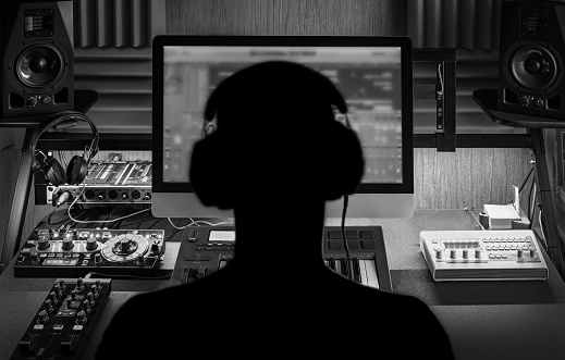 Man produce electronic music in project home studio. Black and white monochrome image