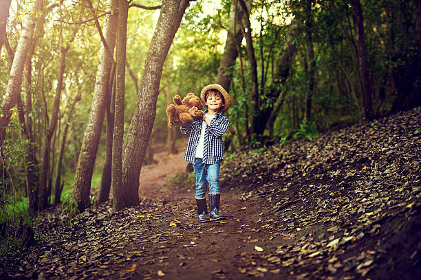 Shot of a little boy sitting in the forest with his teddy bear