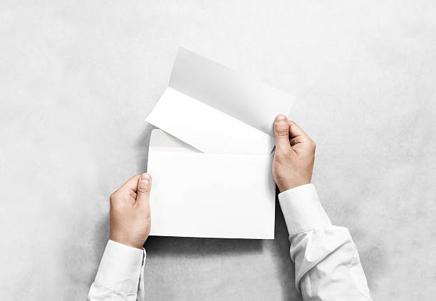 hand holding white blank envelope and folded leaflet mockup, isolated - opening mail letter envelope imagens e fotografias de stock