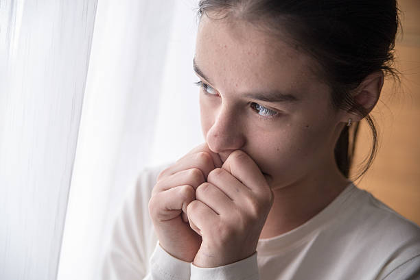 istock Sad girl standing next to window during the day 619264186
