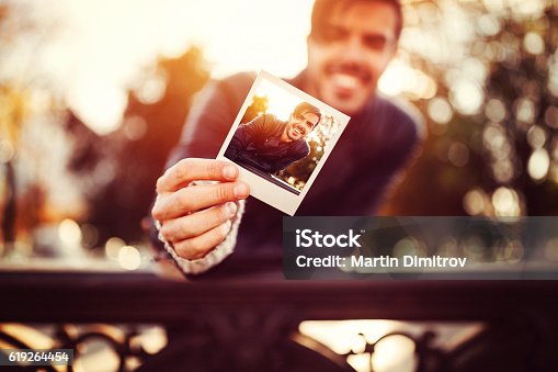 istock Young man showing instant selfie 619264454
