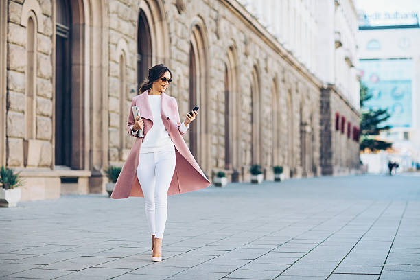 mujer de moda enviando mensajes de texto al aire libre - contemporary elegance telephone urban scene fotografías e imágenes de stock