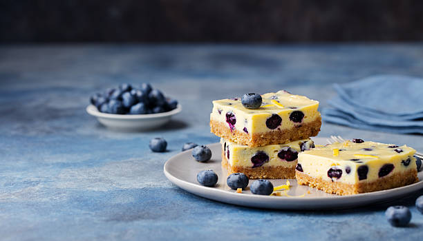 Blueberry bars, cake, cheesecake on a grey plate on blue stone background.