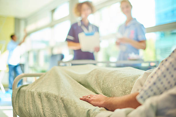 senior nurse chatting to student nurse and patient - hospital patient bed nurse imagens e fotografias de stock