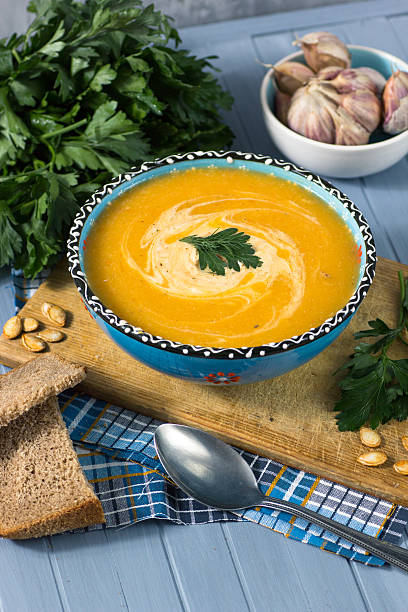 istock cream soup with pumpkin, greens, seeds and bread on blue 619266822