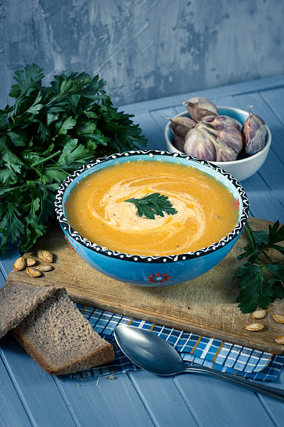 istock cream soup with pumpkin, greens, seeds and bread on blue 619266936
