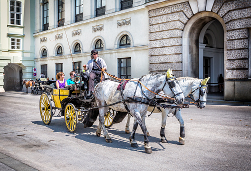 Vienna, Austria - June 24, 2016: People have a ride in the fiaker and pass the Hofburg  in Vienna. The fiaker first was build in the 18 century in the street Rue de Saint Fiacre.