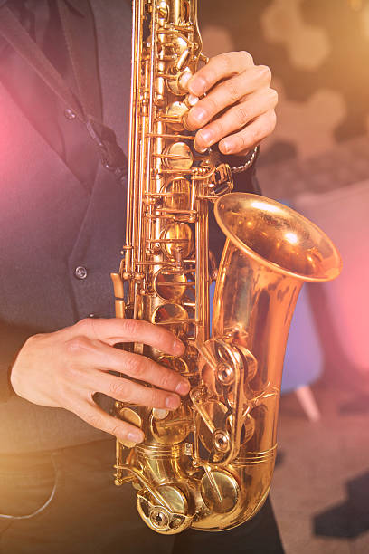 istock Young man in a suit hold saxophone 619268778