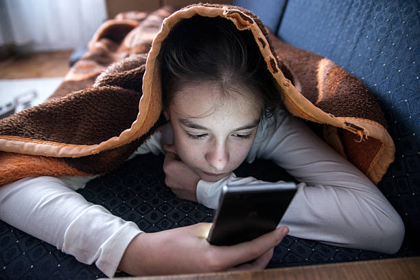 istock Female teen using phone in bed during the day 619269082