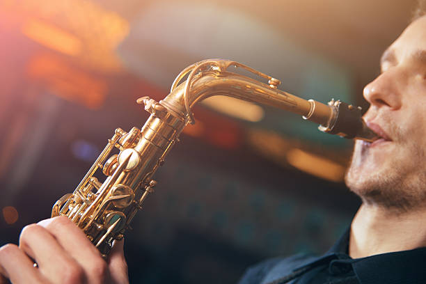 istock Young man in suit playing on saxophone 619269088