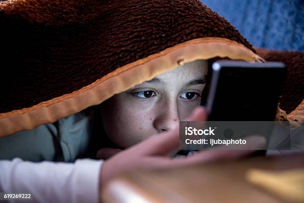 Girl In Bed Texting On Smartphone Stock Photo - Download Image Now - Teenager, Adolescence, Child