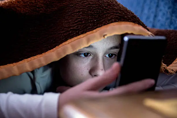 Photo of girl in bed texting on smartphone