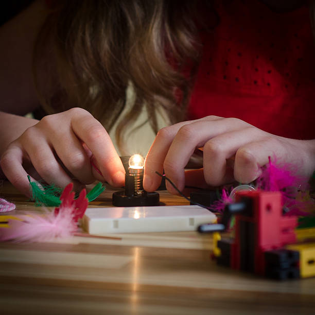 Girl Connects Lightbulb Female Child Wires a LIghtbulb Playing With Electronics Kit girl flex stock pictures, royalty-free photos & images