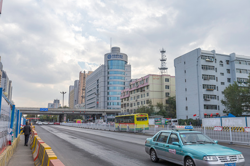 Urumqi, Xinjiang, China - October 4, 2016: Urumqi street view. Bus and Taxi on the road, business buildings on the road sides, incidental people on the background.