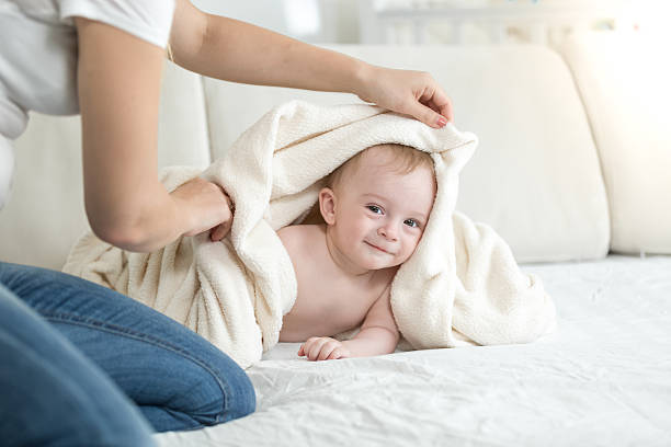 istock Mother covering her baby lying on bed after bathing 619274676