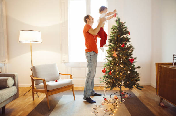 pai e filho decorando a árvore de natal - christmas family child christmas tree - fotografias e filmes do acervo