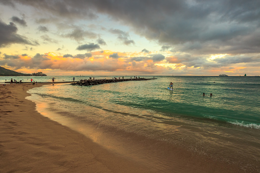 Waikiki, Oahu, Hawaii, United States - August 20, 2016: twilight at Waikiki beach. Waikiki beach is a beautiful place to enjoy the sunset over the ocean. People practice surfing paddling and swimming.