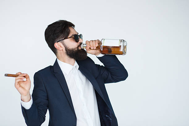 uomo che tiene un whisky e beve dalla bottiglia - cigar whisky men smoking foto e immagini stock