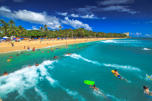 Waikiki, Oahu, Hawaii, United States - August 27, 2016: Boogie boarding, bodyboarding also called, is a popular water sport practiced in Waikiki Beach near the Waikiki Pier at Queens Surf Beach in Honolulu.